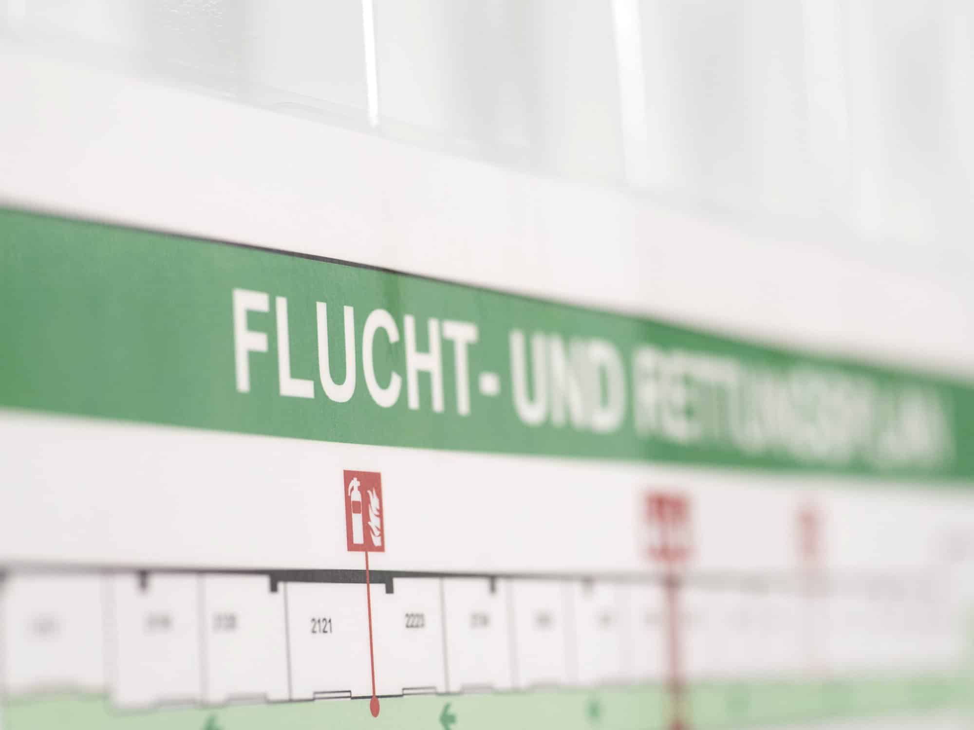 Aushang eines Flucht- und Rettungsplans mit grüner Kopfzeile und dem Brandschutzzeichen für einen Feuerlöscher